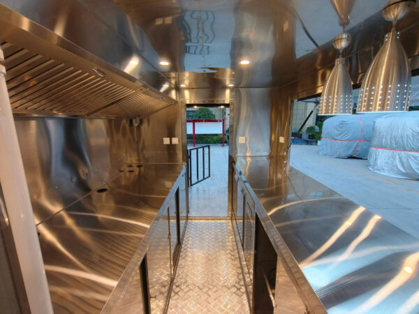 Interior of a custom BBQ food trailer with stainless steel counters and ventilation, built by Luxe Custom Co.