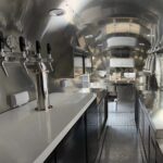 Bar trailer interior with stainless steel counters, ventilation hoods, and storage, built by Luxe Custom Co.