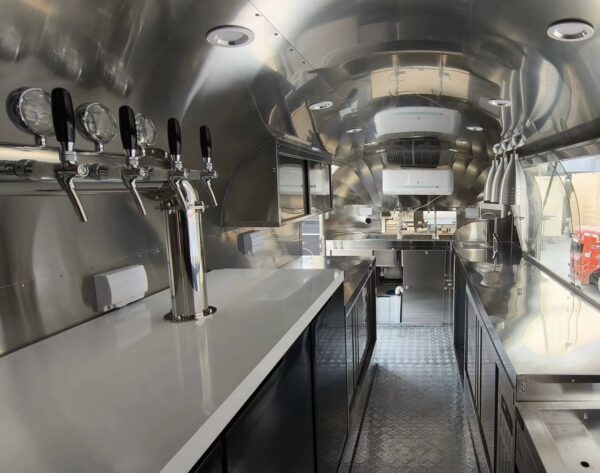 Bar trailer interior with stainless steel counters, ventilation hoods, and storage, built by Luxe Custom Co.