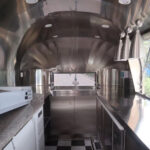 Interior of a 16ft pizza trailer with stainless steel counters and wood-fired oven, built by Luxe Custom Co.