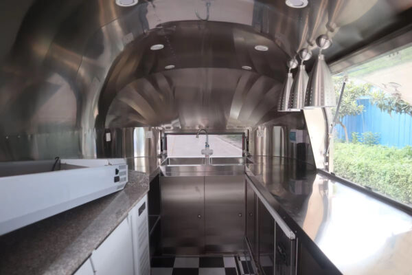 Interior of a 16ft pizza trailer with stainless steel counters and wood-fired oven, built by Luxe Custom Co.
