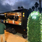 Exterior of a mobile food trailer with barista serving coffee, available in concession trailers for sale by Luxe Custom Co.