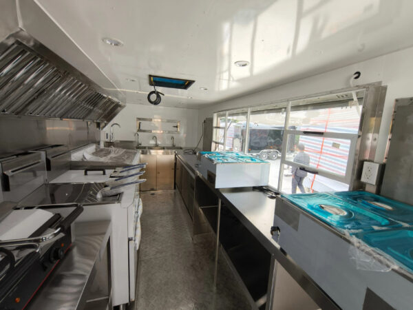 Stainless steel interior of an 18ft food truck trailer with griddle, fryer, and ventilation, crafted by Luxe Custom Co.