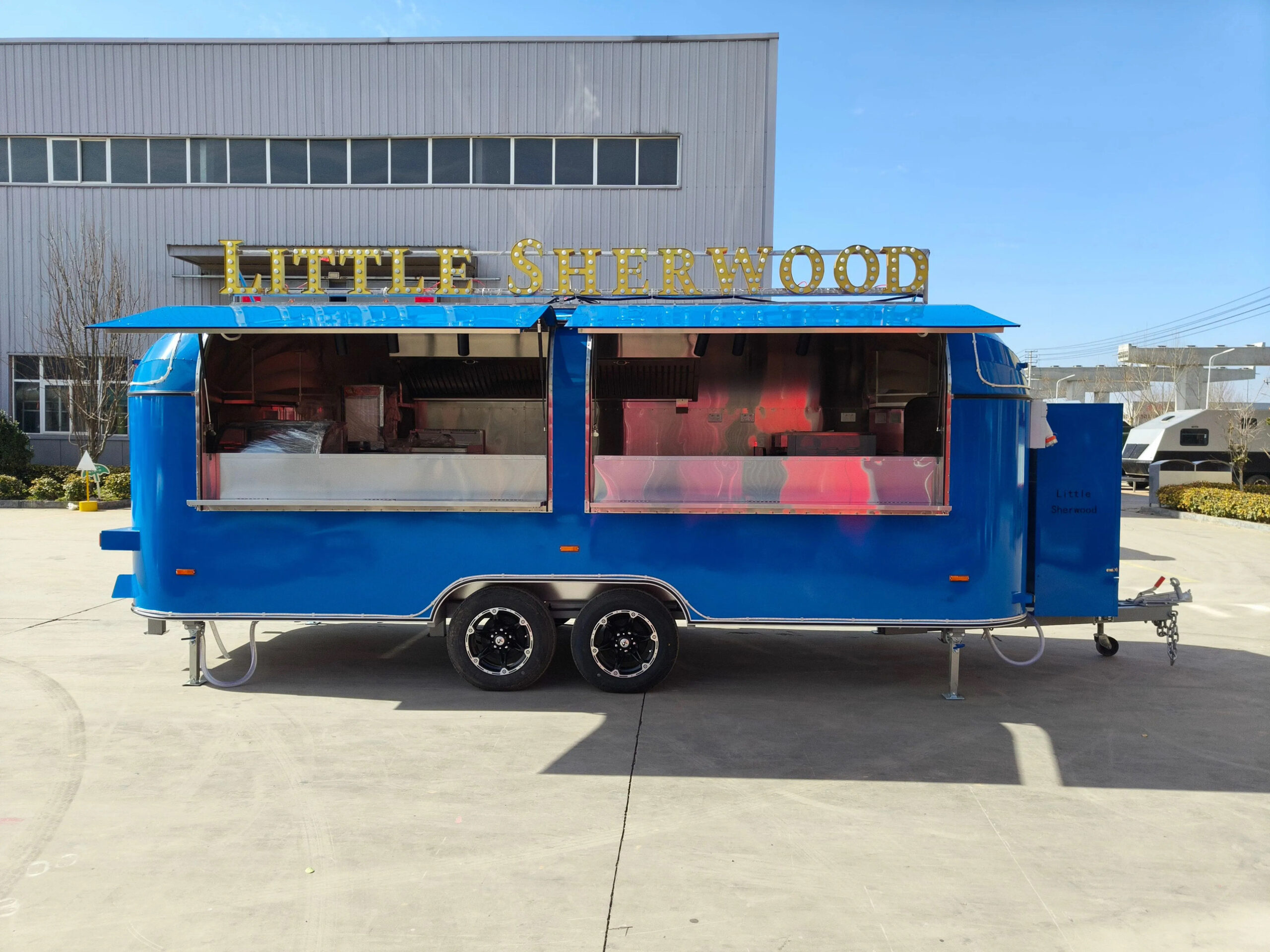 Side exterior of an 18ft round-body mobile food trailer with branded wrap, built by Luxe Custom Co food trailer builders.