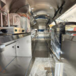 Interior of a custom food trailer with stainless steel counters and commercial blender for ice cream, crafted by Luxe Custom Co.
